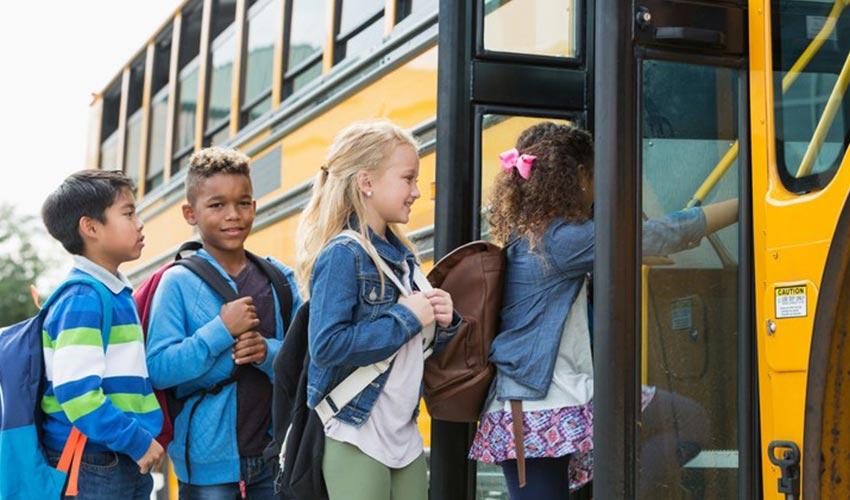 A group of children getting on a school bus.