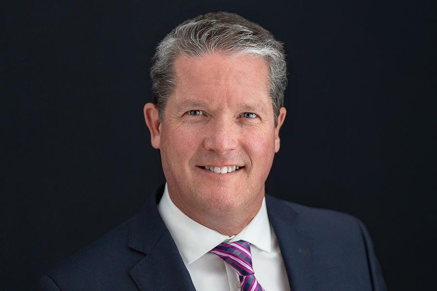A man in a suit and tie smiling for the camera.