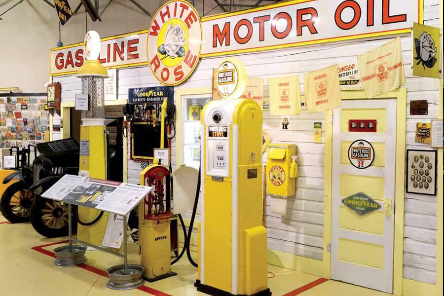 A collection of old cars and gas pumps in a museum.