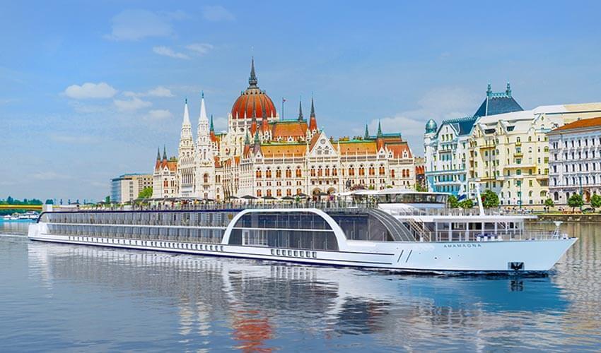A large cruise ship is traveling down the river in front of a building.