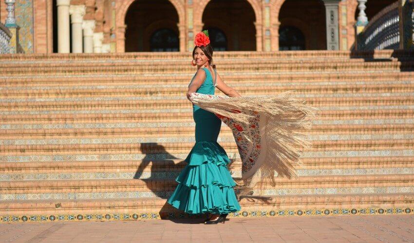 A woman in a flamenco dress standing on steps.