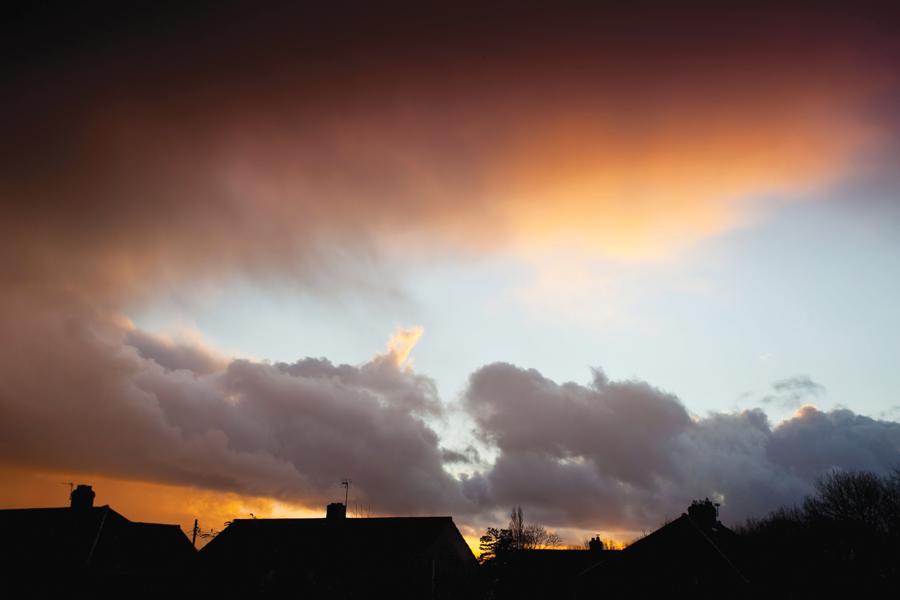 A cloudy sky with houses in the background.