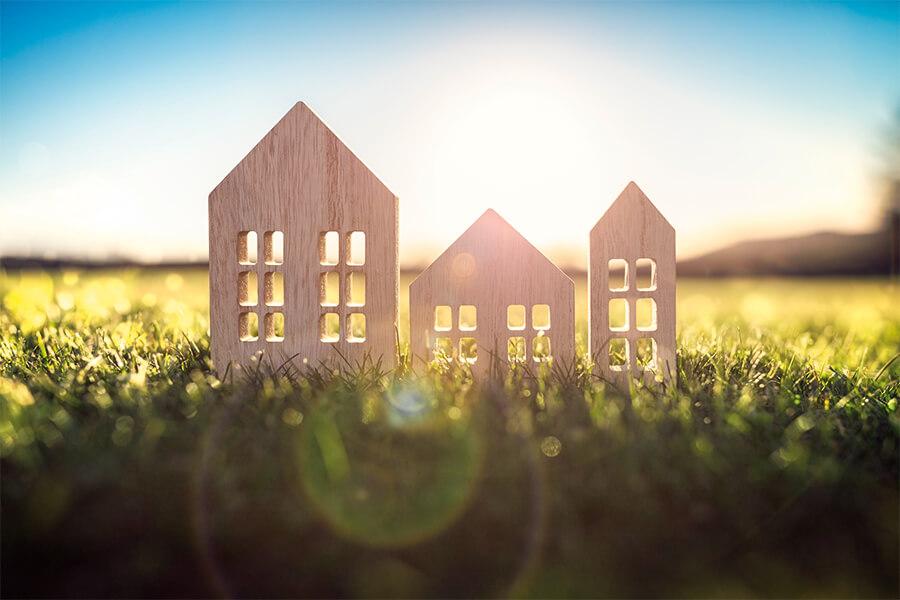 Three wooden houses on a grassy field.