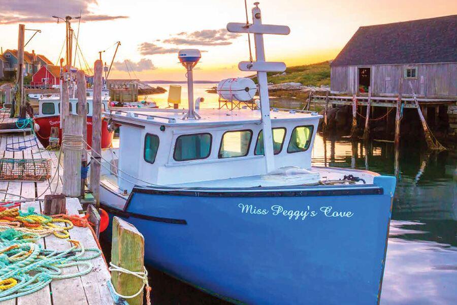 A blue boat docked at a dock at sunset.