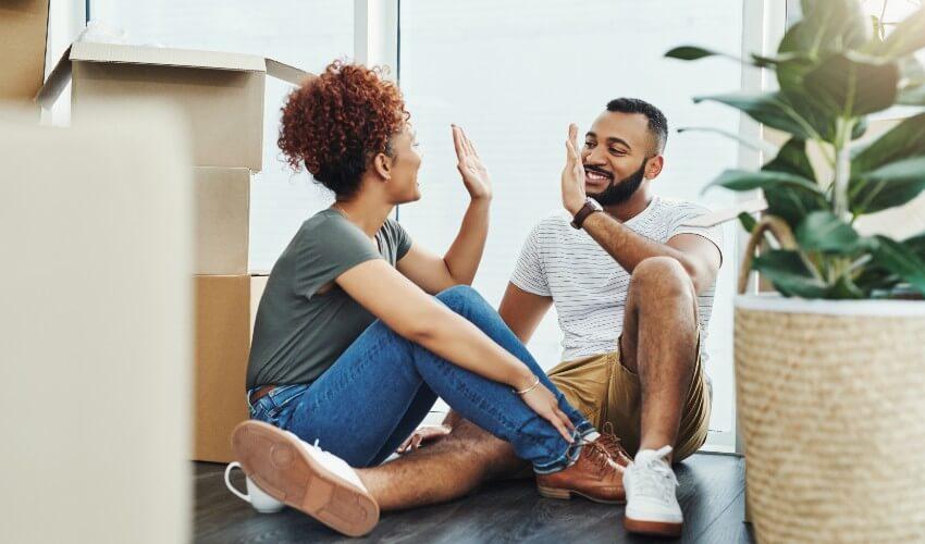 A couple sitting on the floor in their new home.