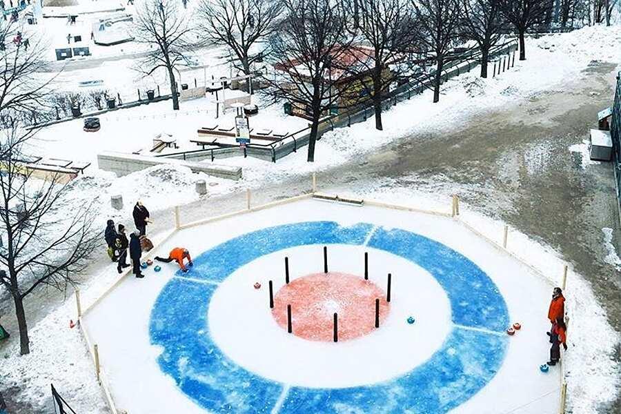 A group of people are playing curling in the snow.