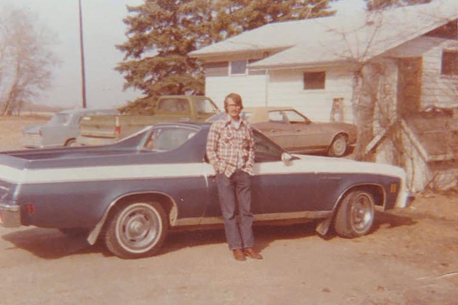 A man standing next to a blue and white car.