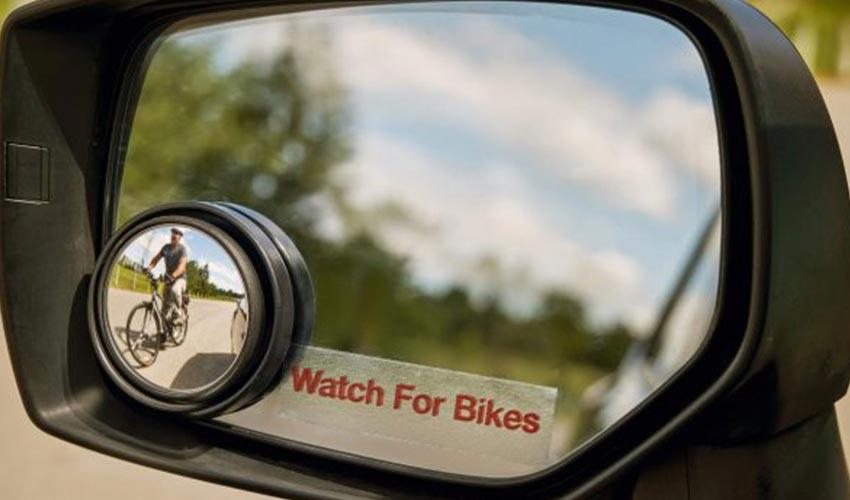 A rear view mirror with a person riding a bike.