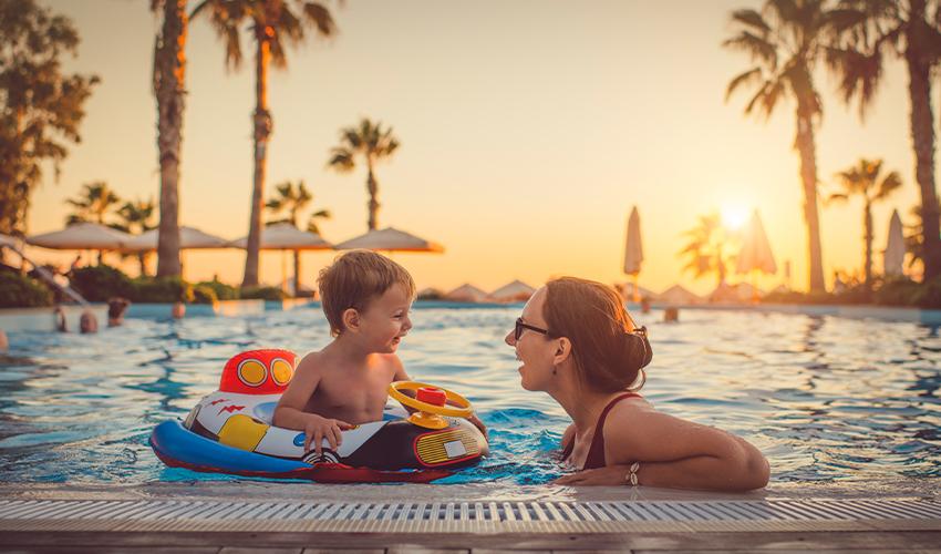 A woman and child in a swimming pool at sunset.
