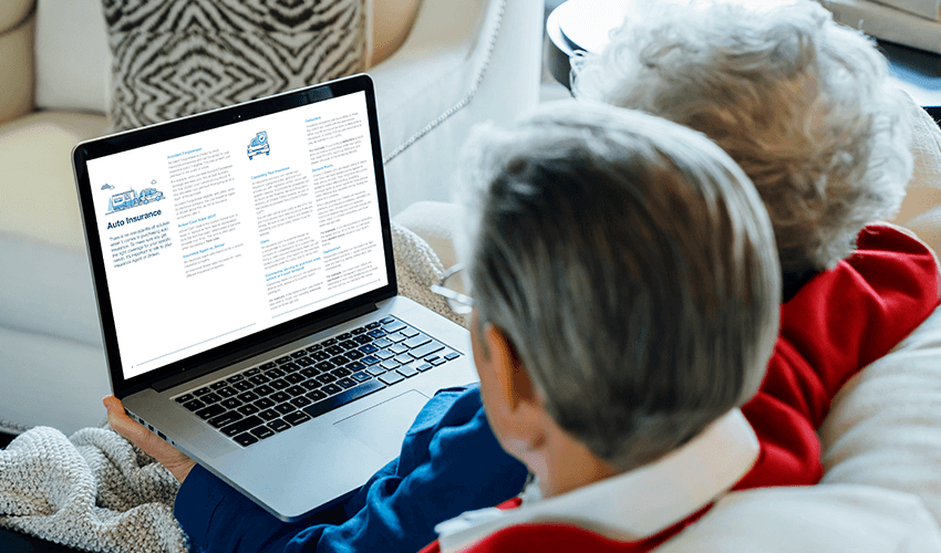 Two elderly people sitting on a couch looking at a laptop.
