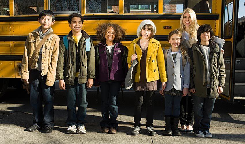 A group of children standing in front of a school bus.