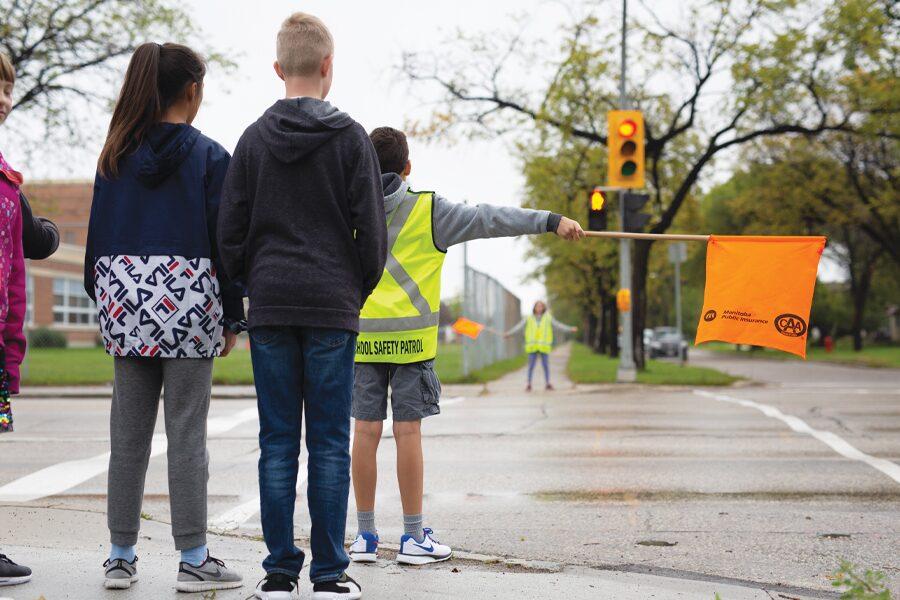 A group of children standing at a traffic light.