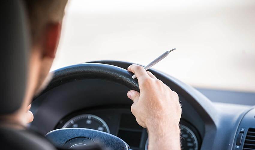 A man holding a pen while driving a car.
