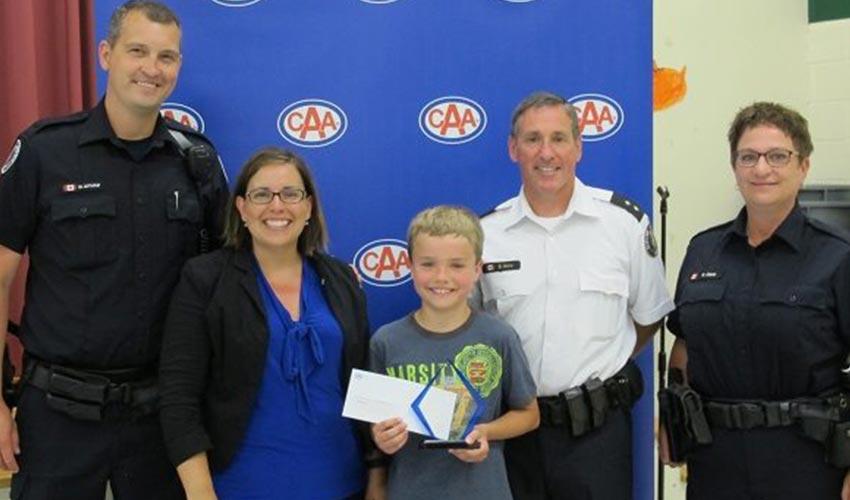 A group of police officers posing with a young boy.