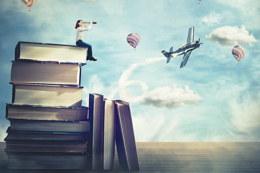 A woman sitting on a stack of books looking through a telescope.