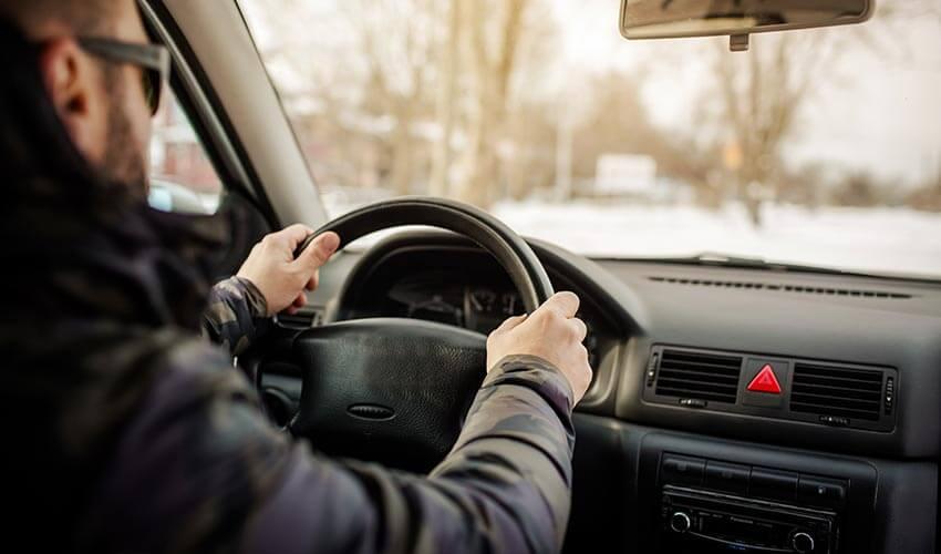 A man driving a car in the snow.
