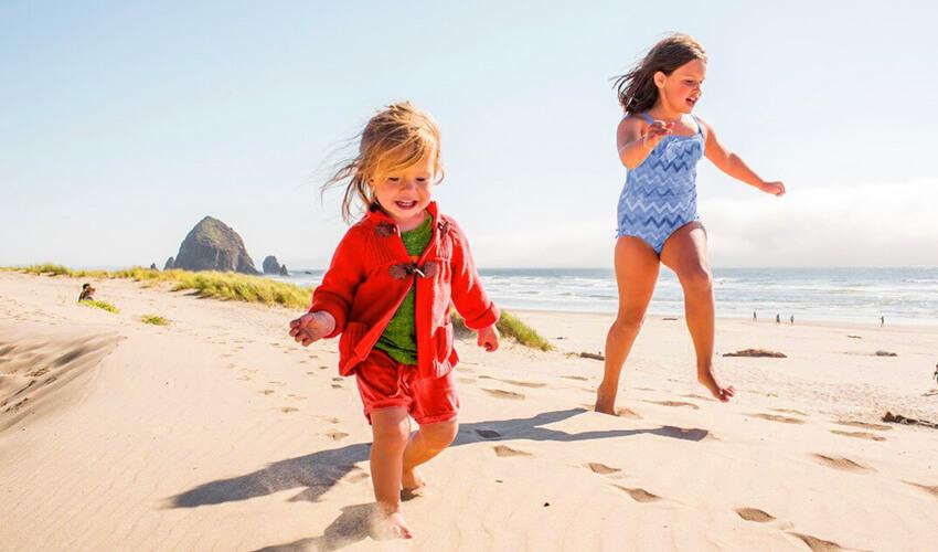 Two children running on a beach.