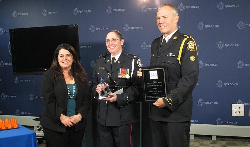 Three people in uniform standing next to each other holding an award.