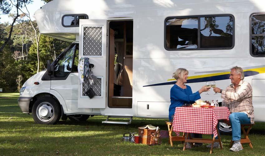 Two people sitting at a table in front of an rv.