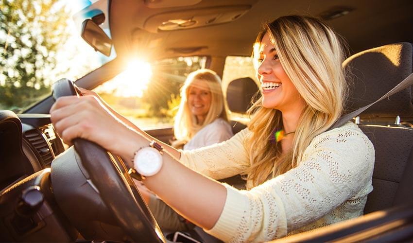 Two women smiling while driving a car.