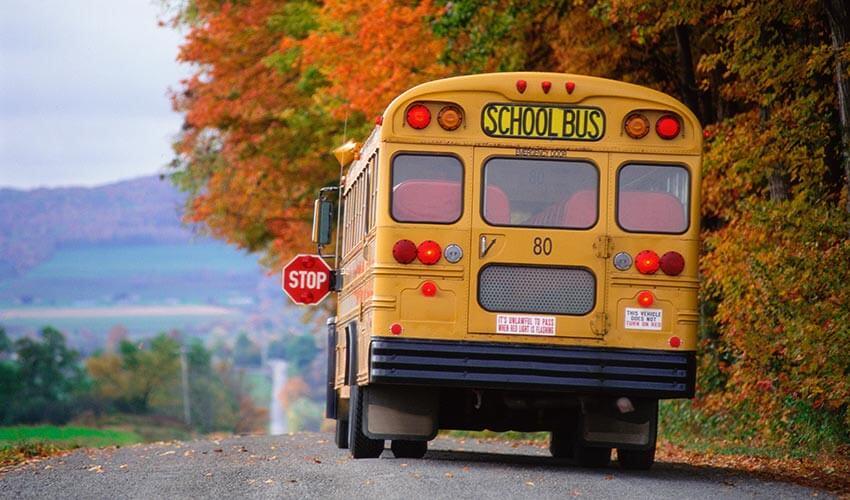 A yellow school bus driving down a country road.
