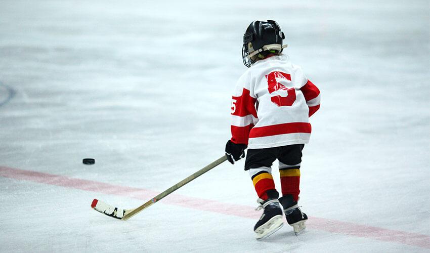 A child is playing hockey on an ice rink.