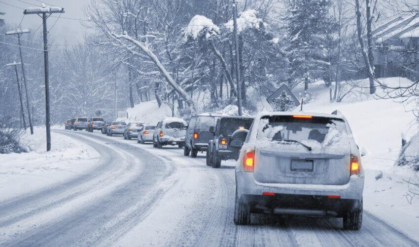 A group of cars driving down a snowy road.