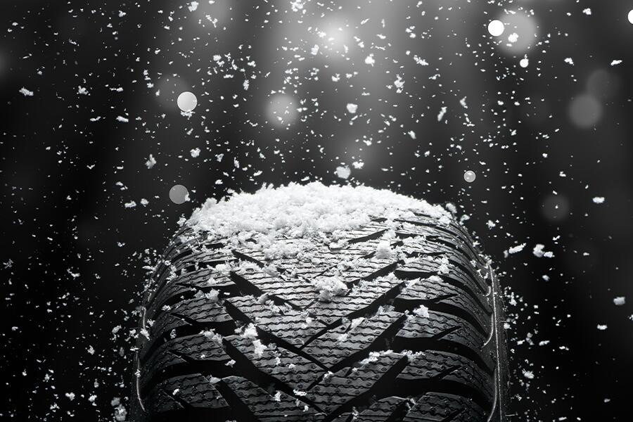 A tire with snow coming out of it on a black background.