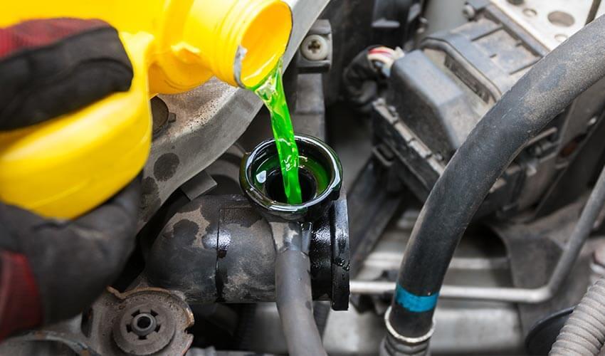 A person is pouring oil into a car engine.