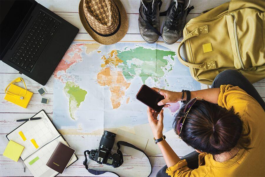 A woman is looking at a world map with her phone.