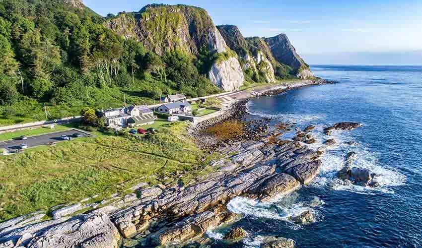 An aerial view of a rocky coastline with a house on it.