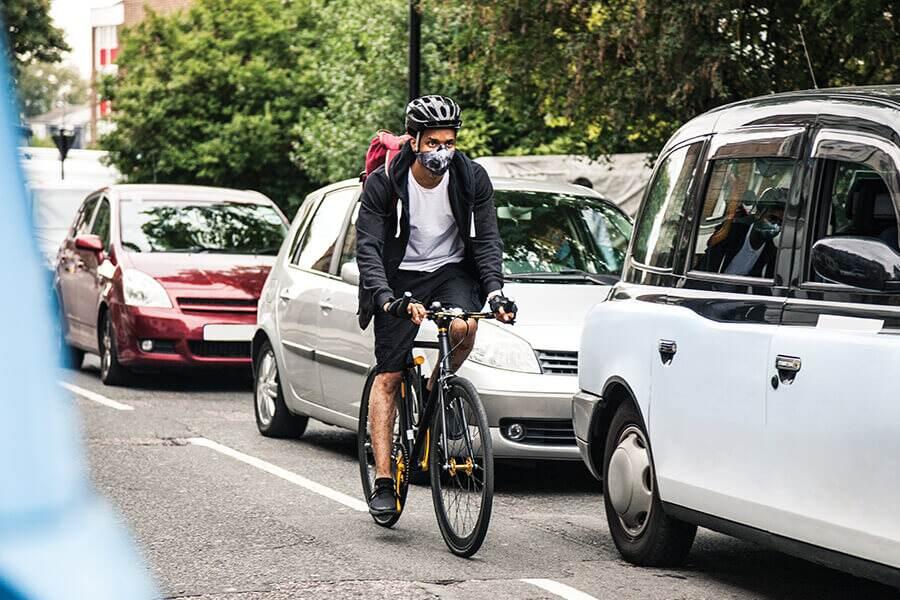 A man riding a bicycle in front of a car.
