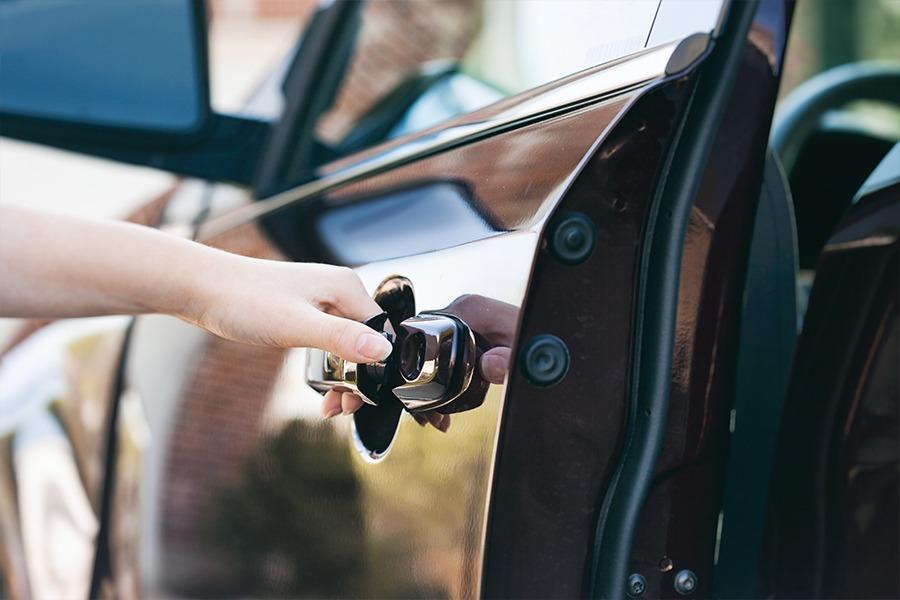 A person opening the door handle of a car.