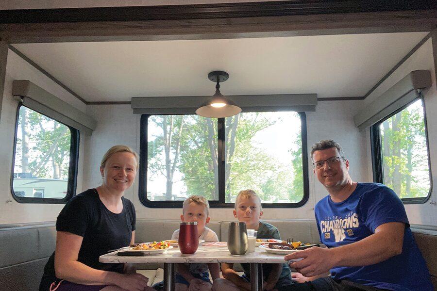 A family sits at a table in an rv.