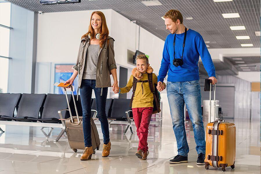 A family with luggage walking through an airport.