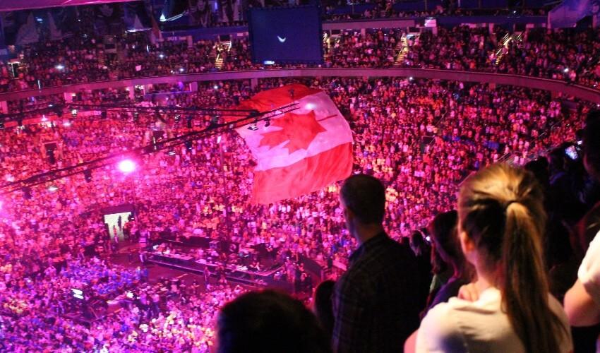 A crowd of people watching a canadian flag in a large arena.
